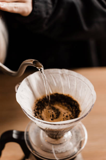 istock Close-up pour over filter with ground coffee in the funnel in focus. Drip filter coffee brewing. Pour over alternative method of pouring water over roasted and ground coffee beans contained in filter. 1473047289