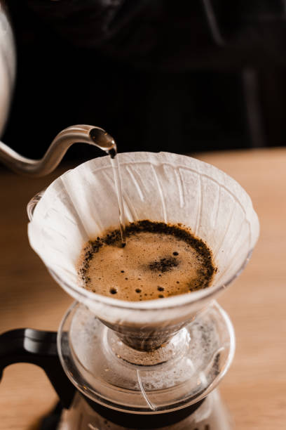 istock Close-up pour over filter with ground coffee in the funnel in focus. Drip filter coffee brewing. Pour over alternative method of pouring water over roasted and ground coffee beans contained in filter. 1473047292