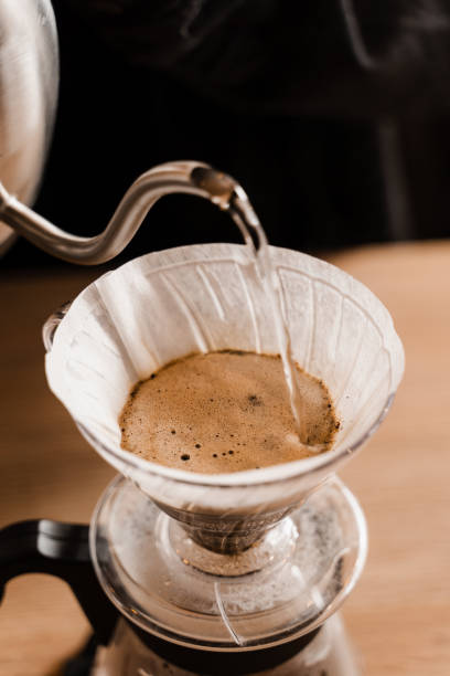 istock Close-up pour over filter with ground coffee in the funnel in focus. Drip filter coffee brewing. Pour over alternative method of pouring water over roasted and ground coffee beans contained in filter. 1473047297