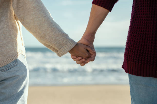 istock Beautiful couple holding hands while walking in a cold winter on the beach. 1473049612