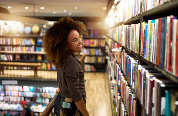 young afro brazilian woman standing and looking shelf book in a bookstore in Ipanema, Brazil stock photo