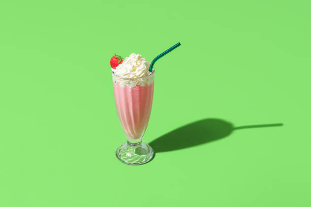 Milkshake glass minimalist on a green background. Homemade strawberries milkshake stock photo