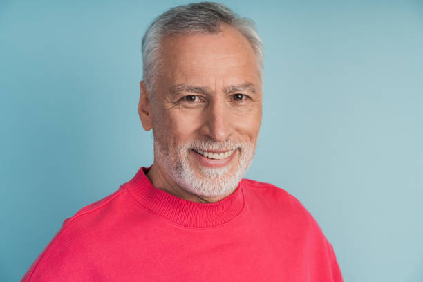 istock Close-up view, senior man smiling on blue background. Attractive man in a bright pullover. 1473054088