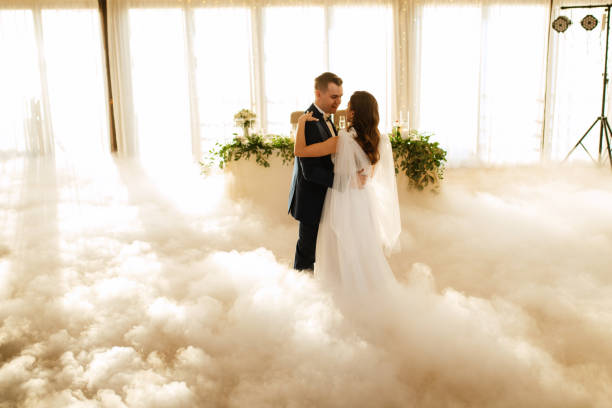 the first dance of the bride and groom inside a restaurant the first dance of the bride and groom inside a restaurant with heavy smoke wedding feast stock pictures, royalty-free photos & images