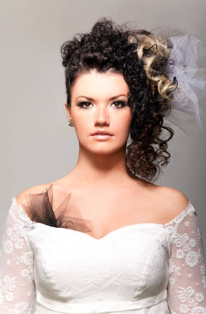 Young female model posing for a studio shot in a white lace dress.