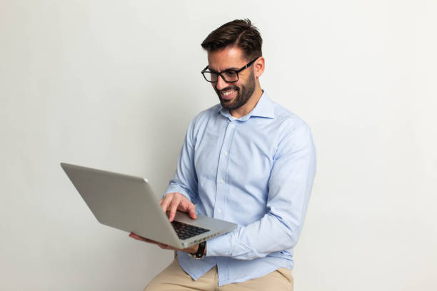 istock Smiling handsome man with laptop on gray background 1473057083