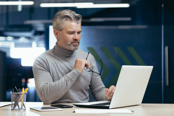 istock Serious thinking mature boss working inside office with laptop, senior businessman typing on keyboard thought about project solution, sitting at workplace 1473058257