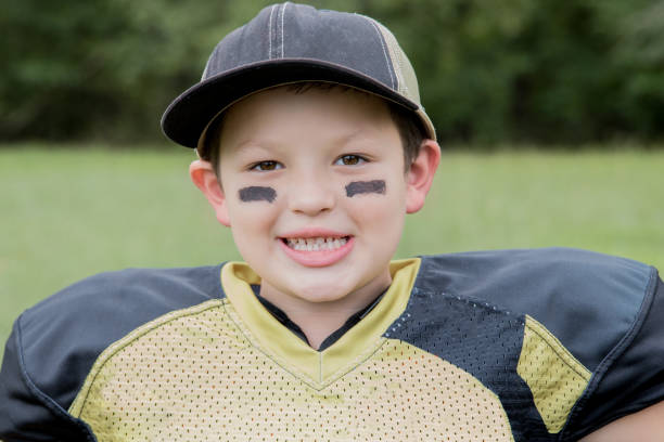 мальчик младшего возраста играет в молодежную лигу американского футбола - youth league american football childhood helmet стоковые фото и изображения