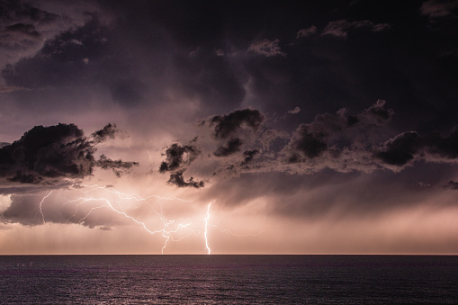 Extreme storm over the ocean with rain, lightning and dark dramatic sky, clouds. Extreme weather scene in Australia.
