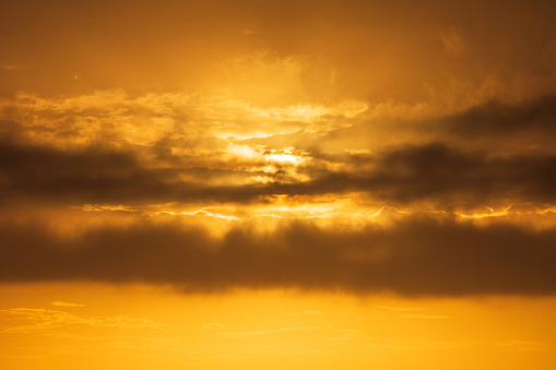 Brilliant warm sunrise and dramatic golden sky with clouds. Summer coastal scene in Australia.
