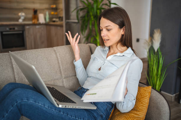 istock Young woman working on laptop while sitting on a sofa at home 1473062692