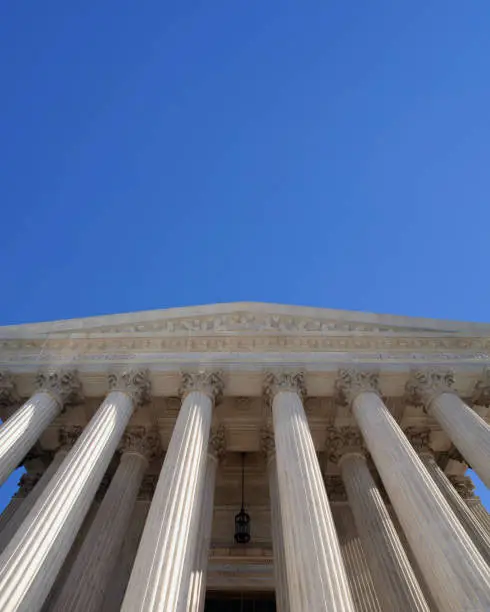 Upward view of the Supreme Court Building in Washington DC with blue sky.