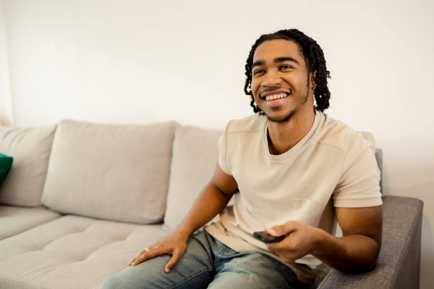 istock Young man enjoying on the sofa, watching TV 1473065182