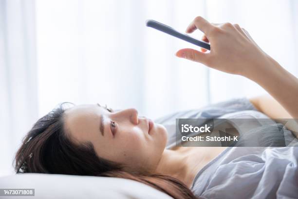 Closeup Of Young Woman Using Smartphone On Bed In The Morning Stock Photo - Download Image Now