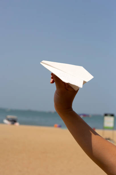 istock Hand holding paper airplane with blue sky 1473074145