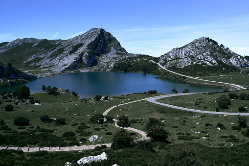 Pedestrian path and road surrounding the lake through the meadows and mountains, Covadonga Asturias, Spain - National park