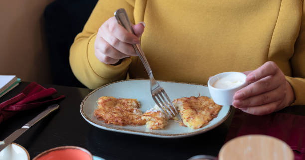 Plus size body positive woman dressed in yellow having breakfast at the cafe early in the morning with selective focus