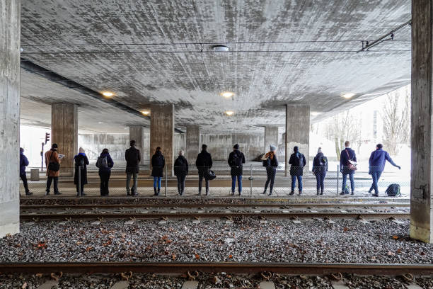 Stockholm, Sweden March 6, 2023 People waiting under a bridge in Liljeholmen for a bus in the early morning to take them to their Scania emplyer  in Sodertalje.