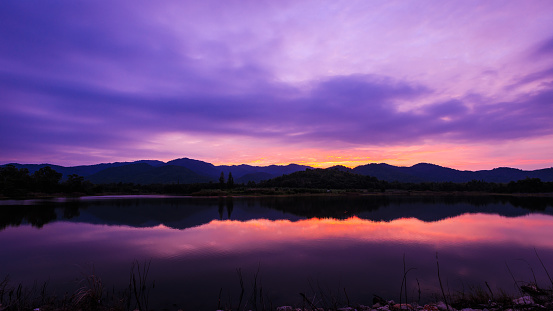 twilight landscape mountain in silhouette over colorful clouds sky background at evening and river in front,