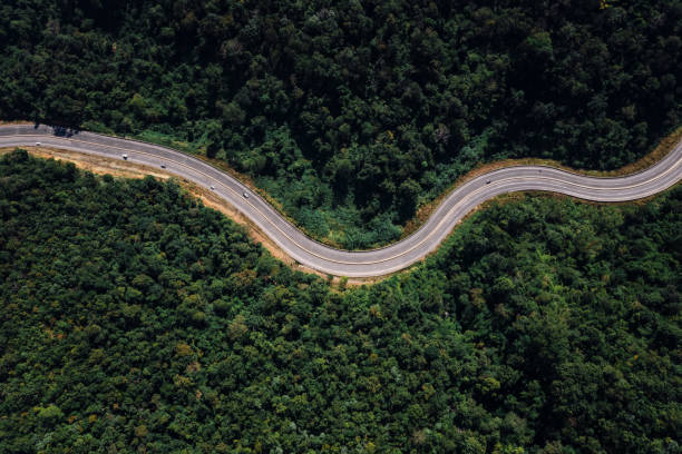 largo camino curvo en el valle que conecta el campo en la selva tropical y el verde bosque de colinas en la parte más septentrional de tailandia - thailand forest outdoors winding road fotografías e imágenes de stock