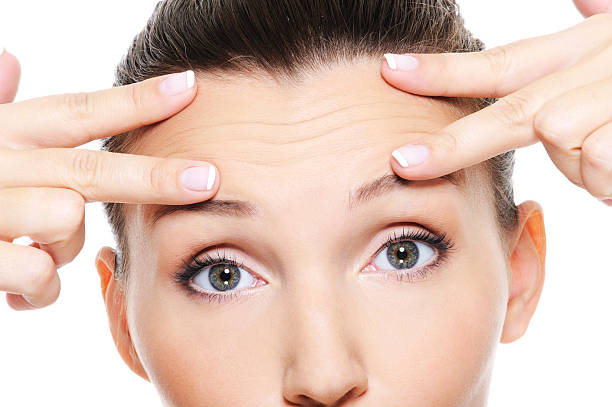 Young woman's face showing wrinkles on forehead Female face with wrinkles on forehead - skincare treatment wrinkled forehead stock pictures, royalty-free photos & images