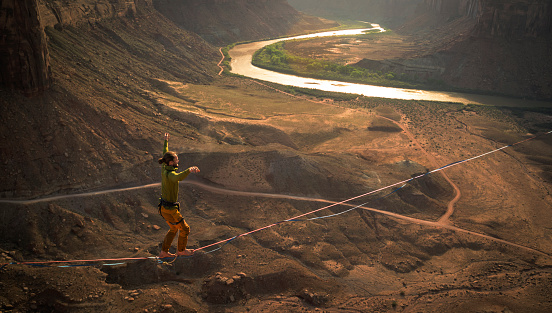 Slack-lining hundreds of feet over canyon in Moab park, Utah