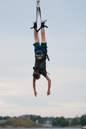 A young man hanging on a bungee cord after a scary jump.