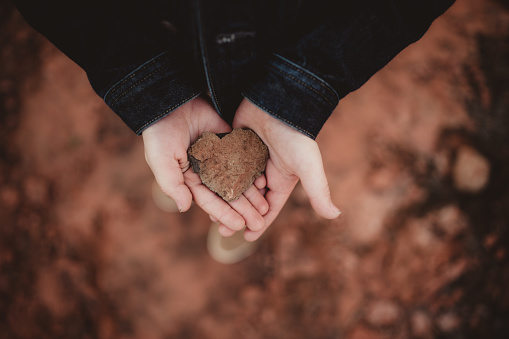 A heart shaped rock in a little boy's hands in the desert