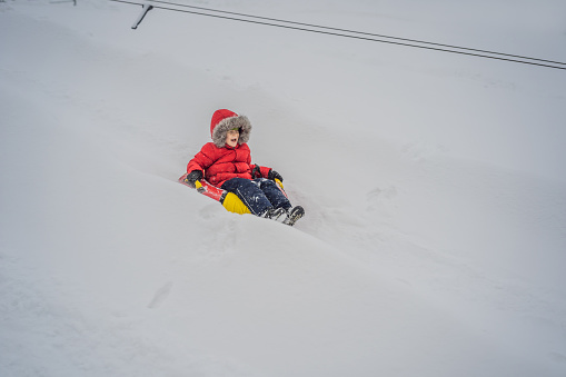 Child having fun on snow tube. Boy is riding a tubing. Winter fun for children.