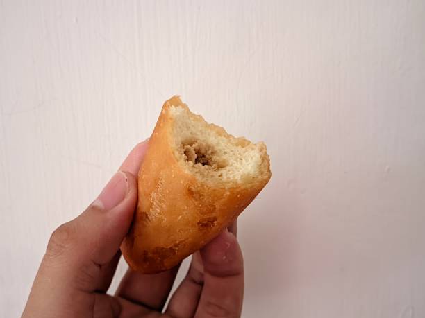 istock Croquettes cake that have been bitten in half in hand holding against a white wall background 1473096810