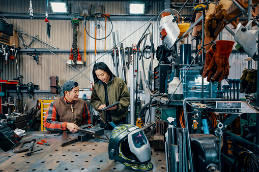 Two engineers looking at a digital tablet in a metal fabrication workshop in Japan