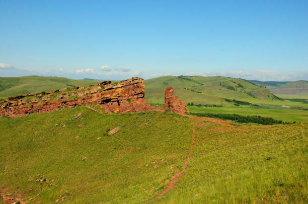 the ruined remains of an ancient wall of layered red sandstone running along the top of a gentle hill in a huge picturesque valley. - dirty pass imagens e fotografias de stock