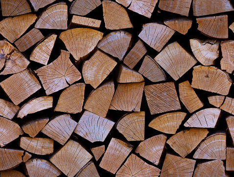 Seamless pattern with firewood on a black background. Repetitive full woodpile. Stock wood for heating. Concept of global fuel crisis and energy impasse