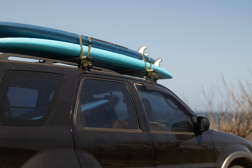 SUV parked at promenade with surfboard on car roof rack