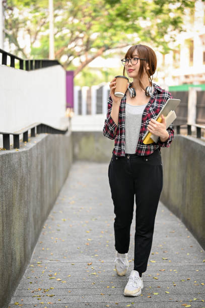 istock Charming Asian female college student walking along the campus building with her stuff 1473104175