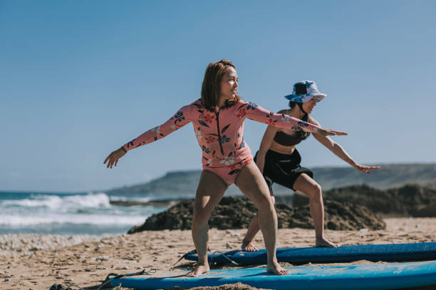 istock 2 asian chinese female surfer learning surfing balancing technique on beach 1473104912