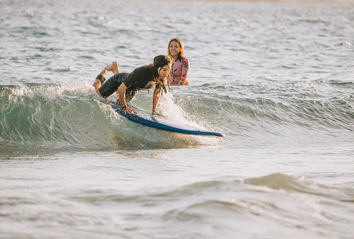 Asian Chinese female surfer enjoying surfing with friend during sunset