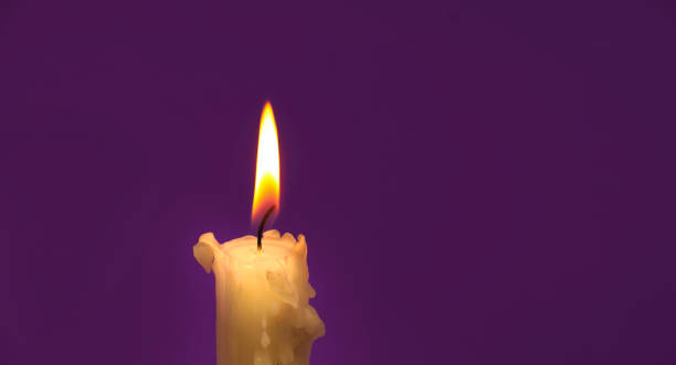 istock Burning wax candle in close up over purple background 1473108672