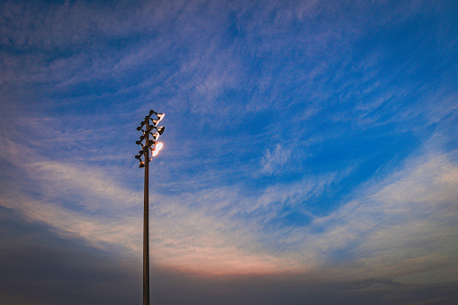 Stadium lights with a blue evening sky and orange clouds.