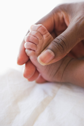 close up of mother's hand holding baby's foot