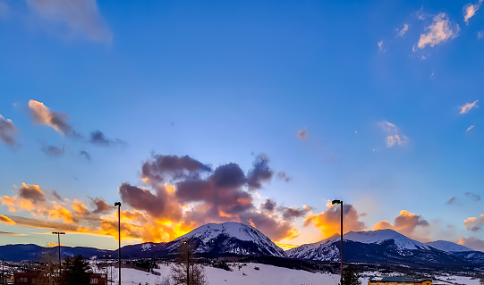 Sun setting behind a snowy mountain peak in Silverthorne, Colorado