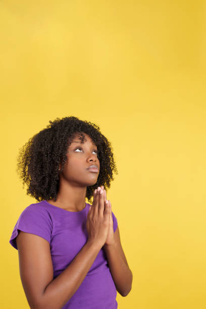 istock Afro woman praying while looking up joining hands 1473117214
