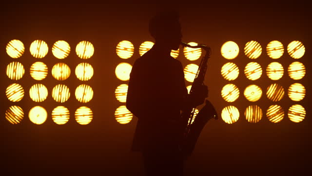 Unknown jazz man saxophonist performing on stage. Player holding modern sax.