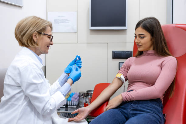 preparazione per l'esame del sangue da parte del medico femminile uniforme medica sul tavolo in camera bianca e luminosa. l'infermiera perfora la vena del braccio del paziente con un tubo bianco con ago. - blood blood sample blood donation tube foto e immagini stock