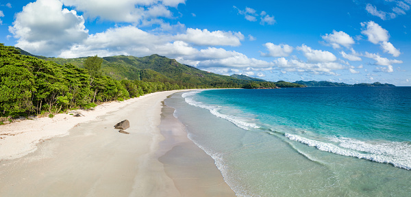 Beautiful Grand Anse Beach Aerial Drone Point of View Panorama. Natural, beautiful empty Beach on Mahé Island under blue summer skyscape with fluffy cloudscape. Grand Anse Beach, Mahé Island, Seychelles, East Africa