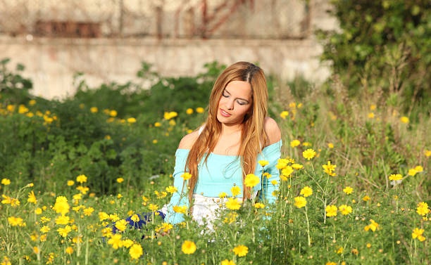 Beautiful young woman sitting in meadow stock photo