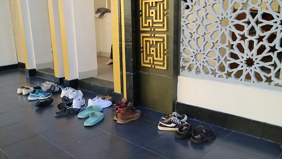Yogyakarta, December 17th, 2023. Shoes, sandals, flip flop and various footwear in front of mosque. Prayer's footwear on the sacred border, outside the mosque while praying.