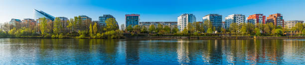 Panoramic view along the leafy promenades of the River Main and modern apartment buildings in the heart of Frankfurt, Germany.