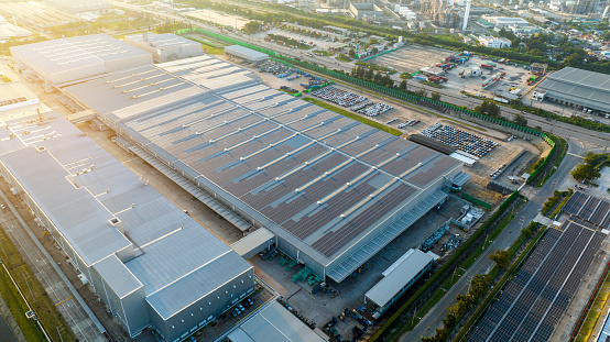 Top view Solar Panels on Warehouse Factory. Solar photo voltaic panels system power or Solar Cell on industrial building roof for producing green ecological electricity. Production of renewable energy at sunset.
