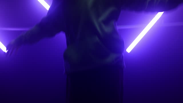 Talented performer breakdancing nightclub ultraviolet backlit. Silhouette dancer